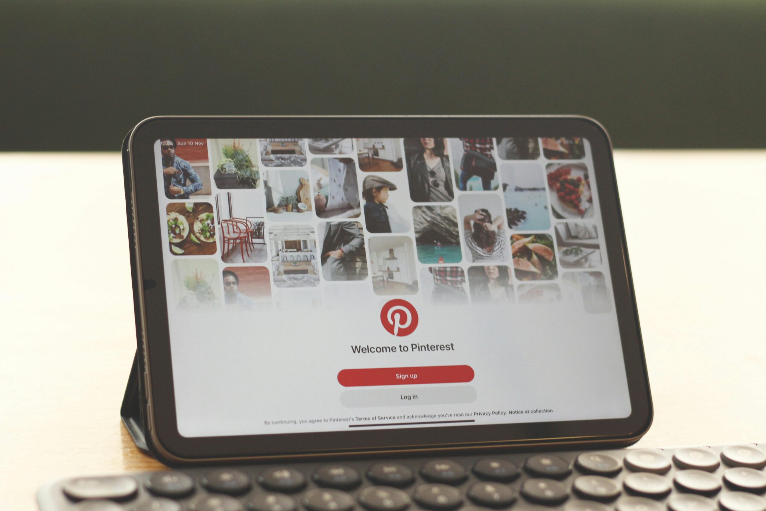 Tablet mit der Pinterest-Startseite auf einem modernen Schreibtisch mit Tastatur.