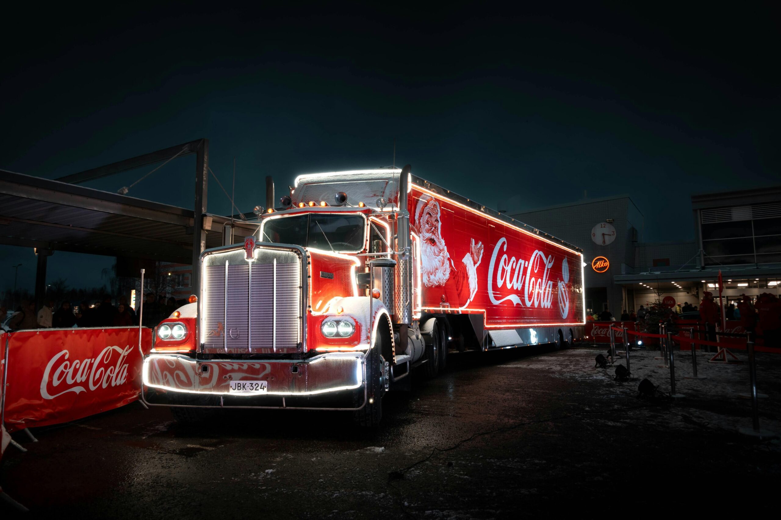 Hell erleuchteter Coca-Cola-Truck mit Weihnachtsmann-Design, aufgenommen bei Nacht fÃ¼r die Feiertage.